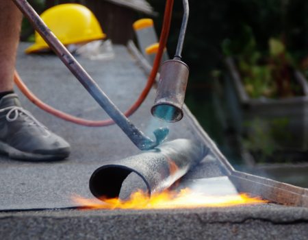 Roof house repair. Putting the roofing felt on the surface with a burner and fire.